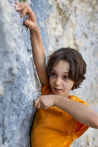 A little rock climber is training to climb a boulder