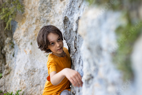 A little rock climber is training to climb a boulder