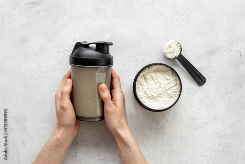 Sport shaker bottle in hands and whey protein in jar. Fitness and gym diet nutrition photo