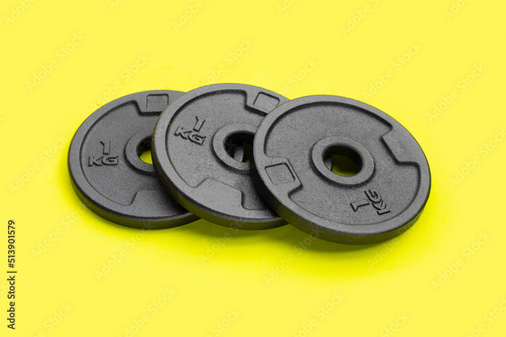 Black weight plates on green background. Gym equipment Black weight plates on green background. Gym equipment