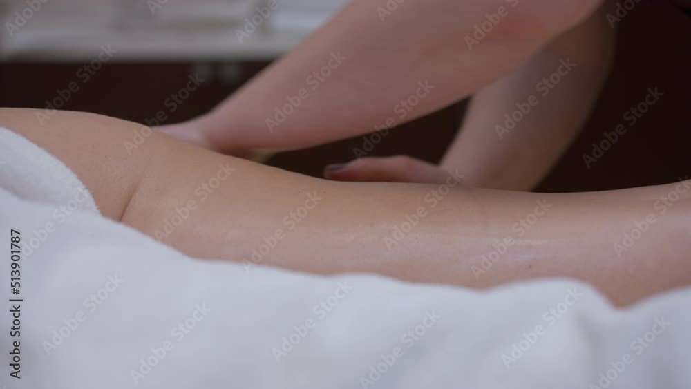 Naked female thigh with massagist hands massaging skin in slow motion. Unrecognizable Caucasian client enjoying service in beauty spa indoors. Body care and pampering concept