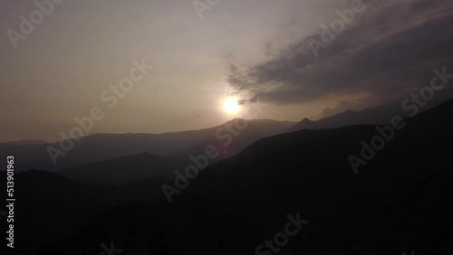 aerial drone view between dark mountains with the background sun shining in the highlands of Lunahuana at sunset with clear sky in 4k  photo
