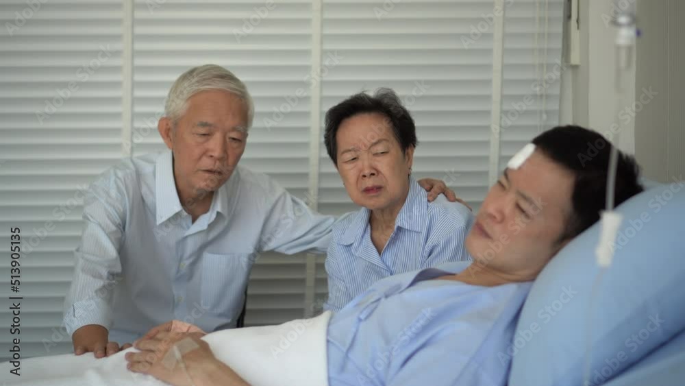 Asian senior parents sad worry about adult son health condition. Man lying hurt injured by accident Asian senior parents sad worry about adult son health condition. Man lying hurt injured by accident