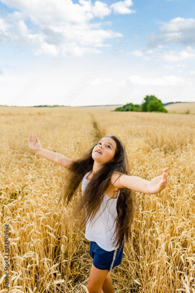 World food crisis. Deficit of grain in the world markets. The girl stands in a wheat field raised her hands to the sky.