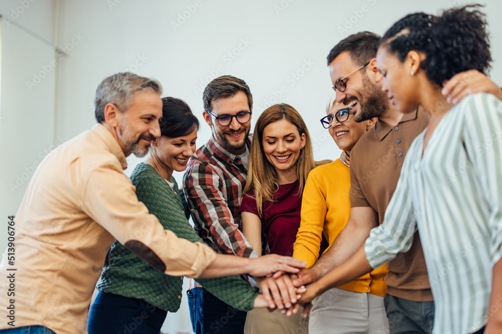 Positive people in the therapy group, looking happy, holding hands in the middle, one over the other. Positive people in the therapy group, looking happy, holding hands in the middle, one over the other.