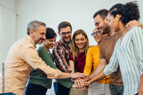 Positive people in the therapy group, looking happy, holding hands in the middle, one over the other.