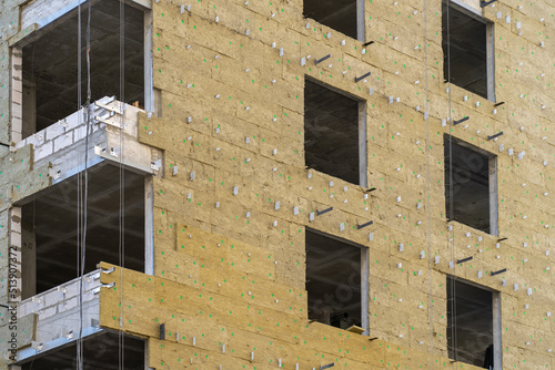 Installation of external wall thermal insulation with rock wool. Exterior passive house wall heat insulation with mineral wool. Insulation facade of multistory residential building. Energy efficiency