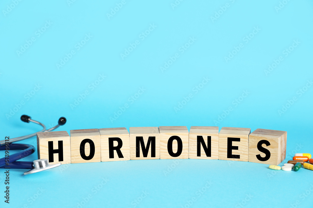 Word Hormones made of wooden cubes with letters, stethoscope and pills on light blue background Word Hormones made of wooden cubes with letters, stethoscope and pills on light blue background