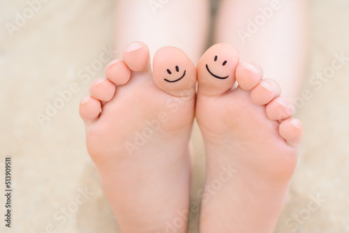 Woman with smiling faces drawn on toes, closeup of foot