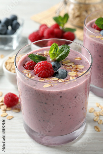 Tasty smoothie with berries, mint and oatmeal on white wooden table