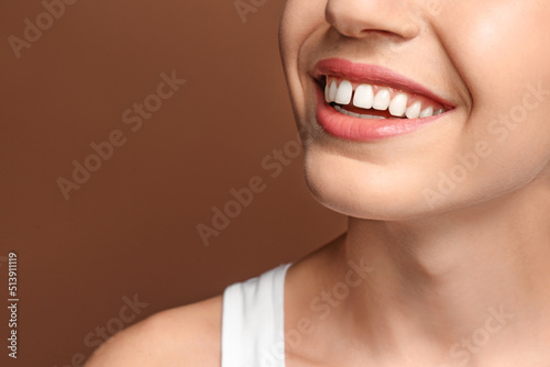 Woman with diastema between upper front teeth on brown background, closeup photo