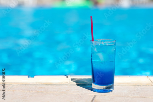 Blue lagoon cocktail with ice near swimming pool. Summer soft drinks.