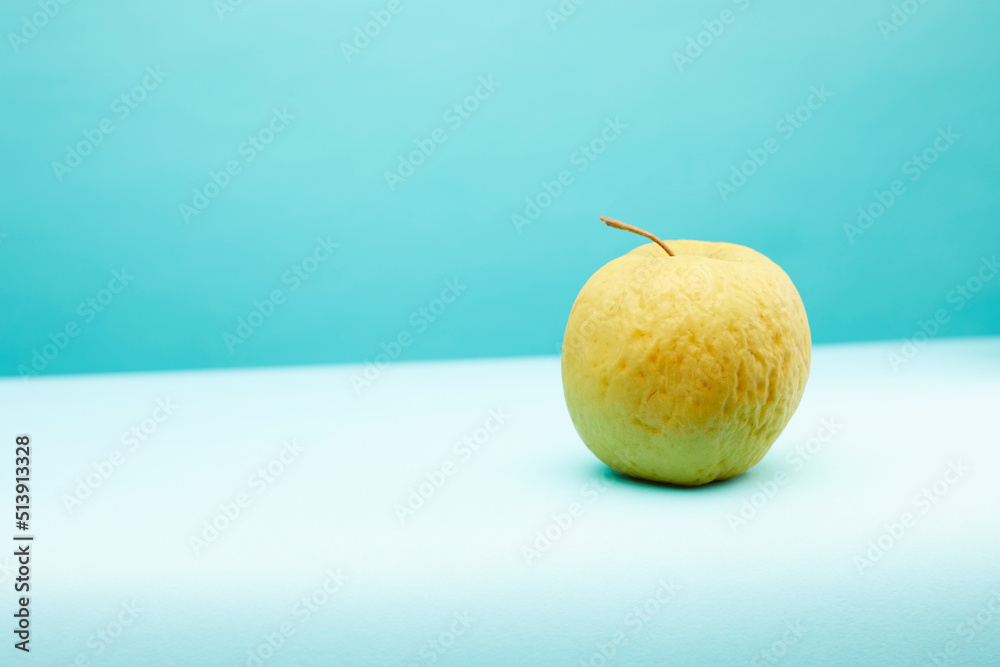 Old, not fresh apple on blue background. Old, not fresh apple on blue background.