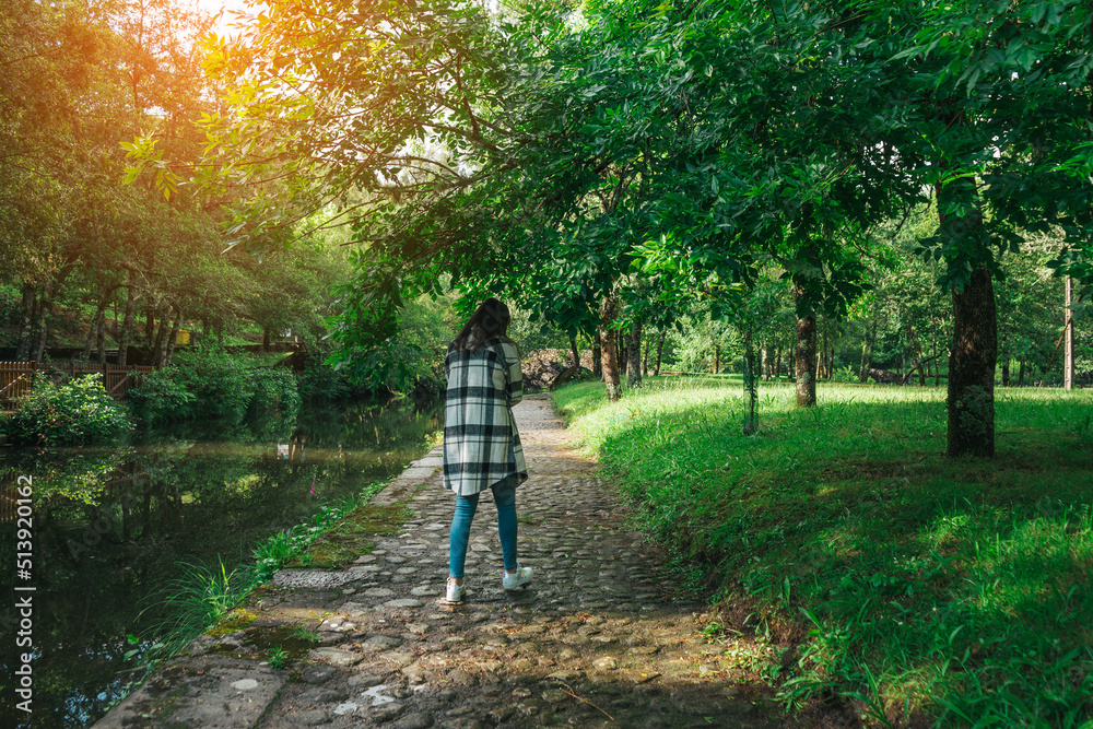 Fototapeta premium Young woman walking by a path along the river