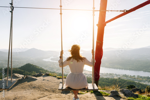 Young woman on a swing looking a beautiful landscape photo