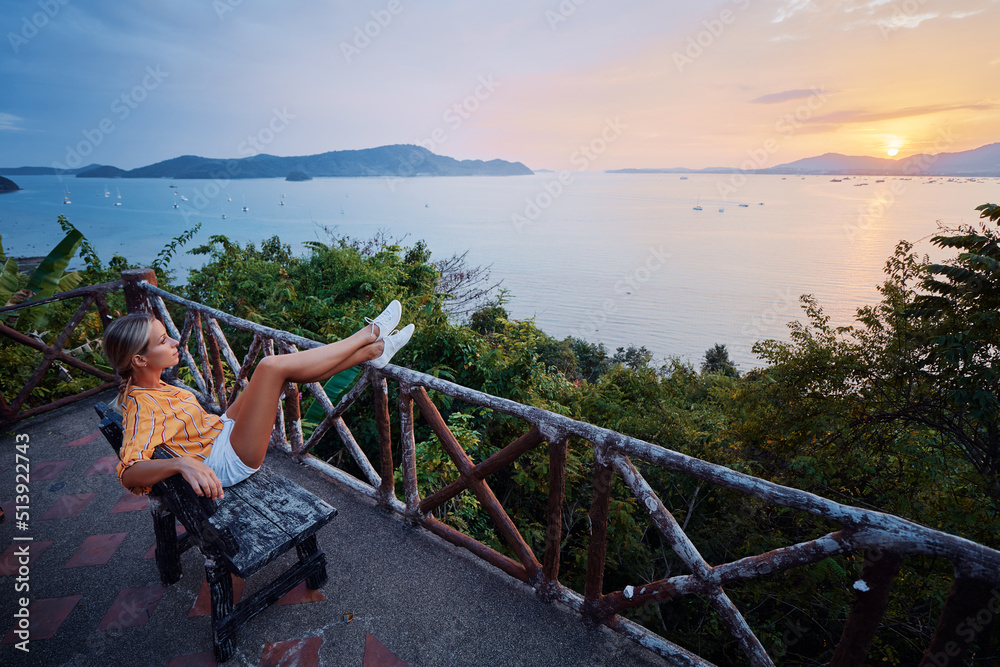 Naklejka premium Traveling by Thailand. Young woman enjoying wonderful sunset on Phuket island view point.