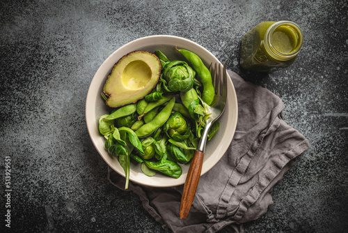 Green healthy salad with spinach, brussels sprouts, avocado in bowl and green detox smoothie