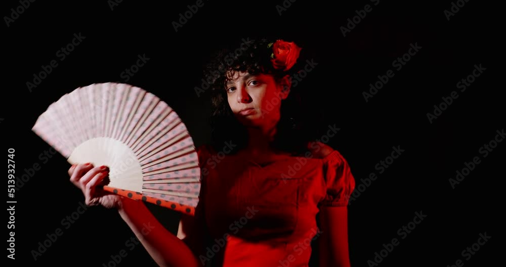 A spanish young lady with a fan shot in slow motion in a dark room