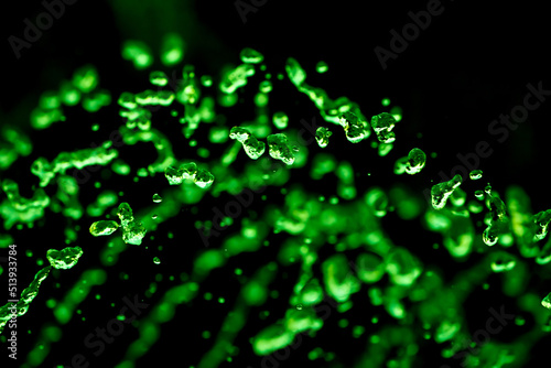 Drops of water splash green water on a black background, concept of freshness drink, watering the rain source of pure water fountain copy space