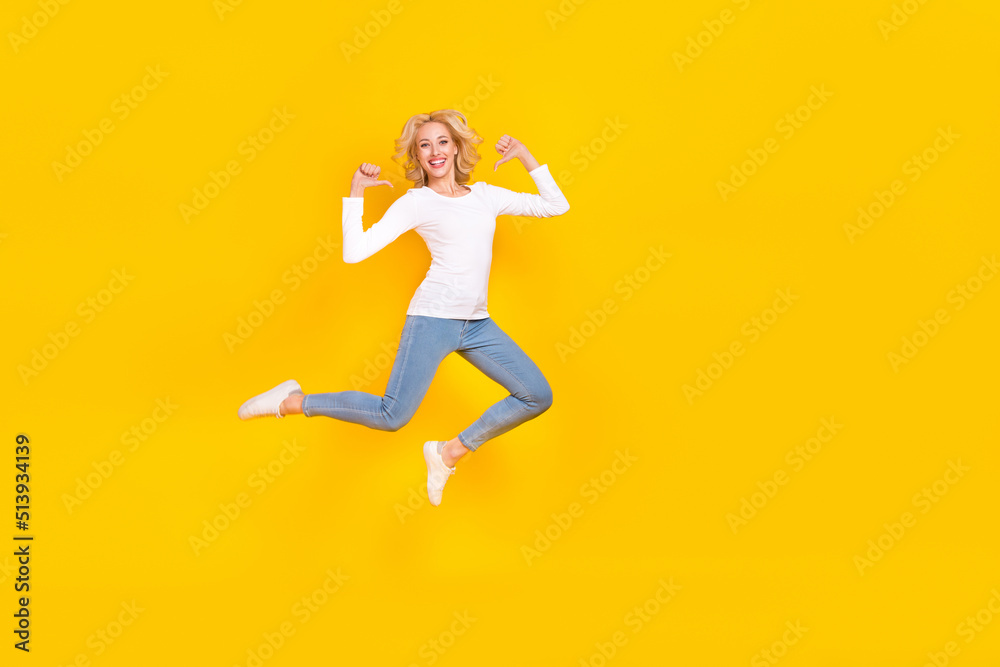 Full length photo of cool millennial blond lady jump index myself wear shirt jeans sneakers isolated on yellow background