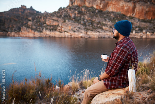 A man enjoys the peace while drinking coffee on mountain camping trip