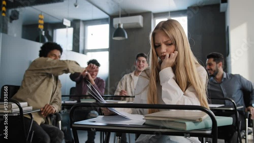 Sad frustrated insecure girl student sitting in classroom at desk suffering from abuse bad attitude ridicule from classmates young woman feeling humiliated distressed lonely concept discrimination