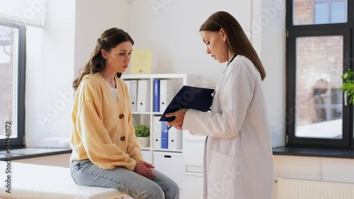 medicine, healthcare and people concept - female doctor with clipboard talking to woman patient at hospital