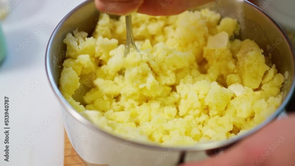 female hand mashes boiled potatoes with a pusher, making mashed potatoes female hand mashes boiled potatoes with a pusher, making mashed potatoes