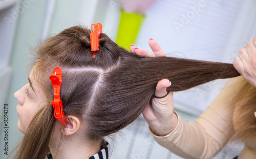 Close-up of the master's hand making a ponytail on a woman's head. The hairdresser makes a hairstyle for a young woman. Barber shop, business concept. Beauty salon, hair care.