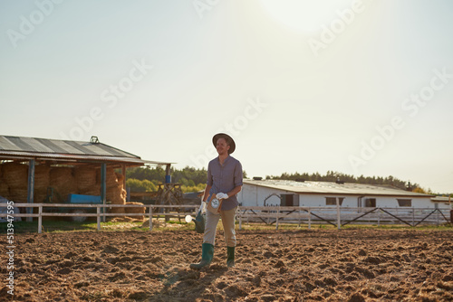 Farmer with water can and seeds on field on farm