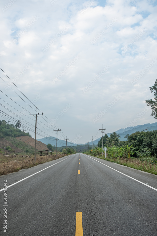 Paved road  Thailand.The asphalt road on both sides of the road is covered with grass.