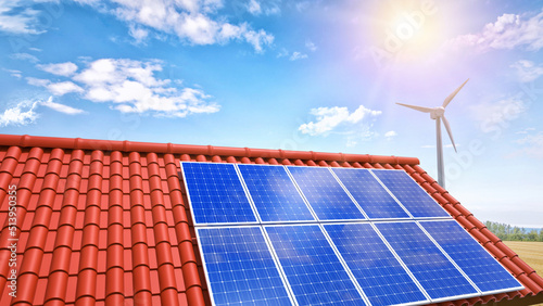 polycrystalline solar panels on roof with wind turbine in background. renewable energy concept. photovoltaic panel on the roof of house.