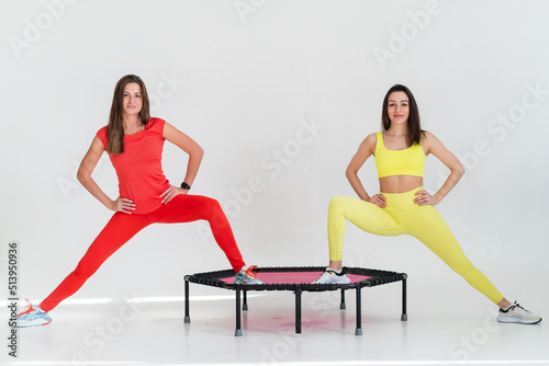 Two adorable fitness women In sportswear jumping on sport trampoline
