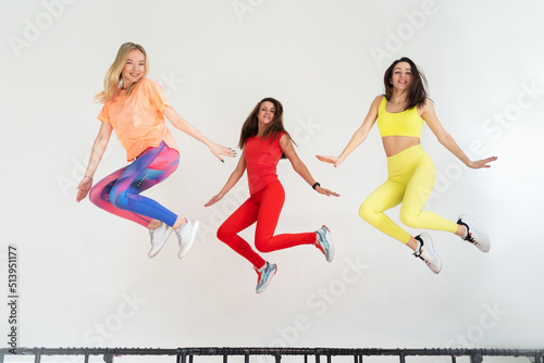 Three adorable fitness women In sportswear jumping on sport trampoline