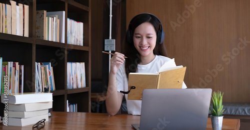 Asian woman wearing headphones study online watching webinar podcast on laptop listening learning education course conference calling, elearning concept.
