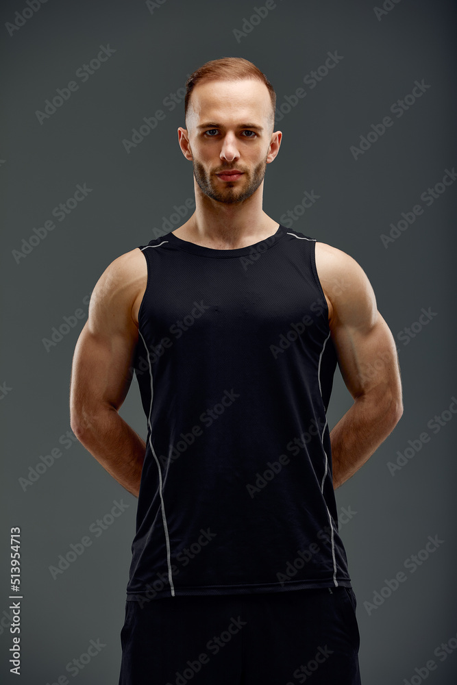 Fototapeta premium portrait of male fitness model in black top relaxing after workout. Grey background with room for text, Copy space.