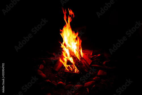 The flame of a bright fire burning at night in the camp, on a black background.