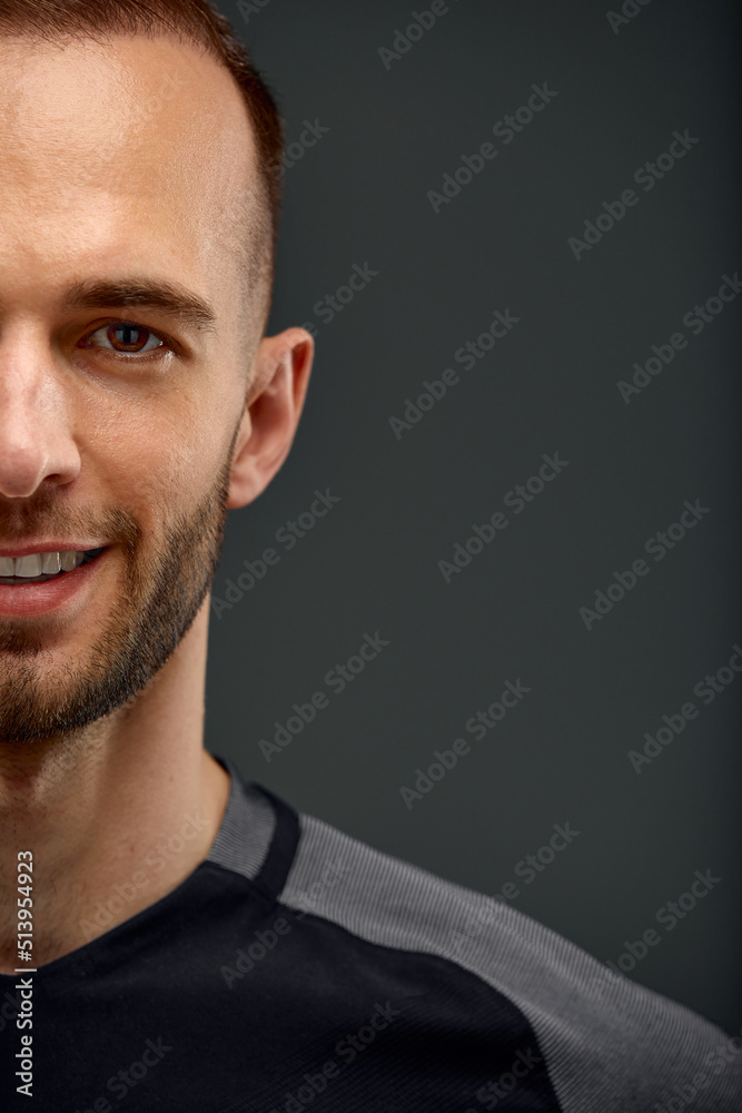 Fototapeta premium Croped portrait of male fitness model in black top relaxing after workout. Grey background with room for text, Copy space.