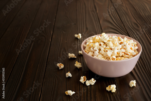 Bowl with popcorn on dark wooden table with copy-space