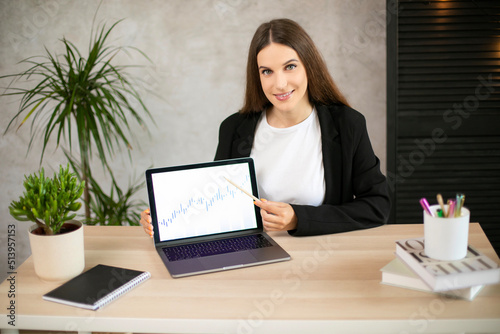 Girl shows on graphic on laptop in office
