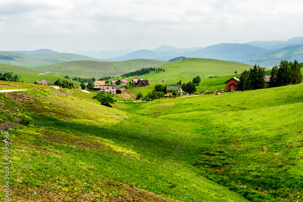 Mountain Village on a Sunny Summer day, with green hills and meadows Mountain Village on a Sunny Summer day, with green hills and meadows