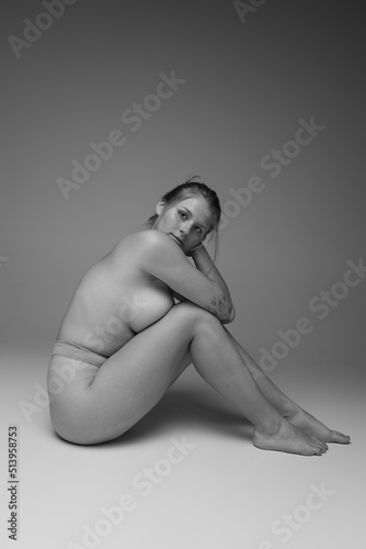 Portrait of young attractive woman sitting on floor, posing in underwear. Black and white photography