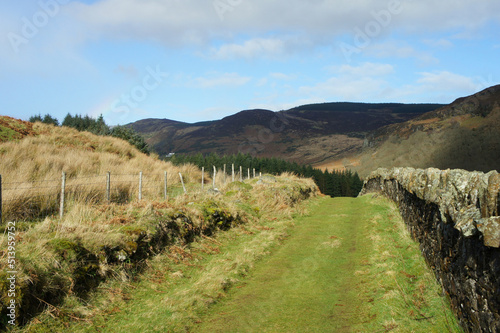 Landscapes of Ireland.A path in a mountain valley running along an old stone wall.