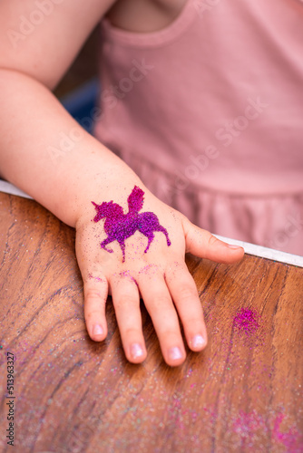 Shimmering sparkling glitter tattoo on a child's hand at a birthday party