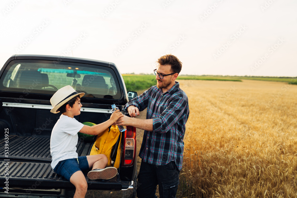 father and son together on wheat field. examine crop. drinking water from bottle father and son together on wheat field. examine crop. drinking water from bottle