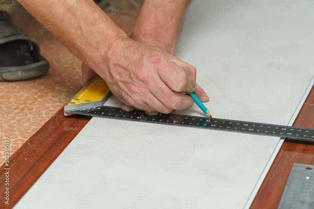 The worker marks the plastic panel with a pencil and tape measure or ruler. Selective focus The worker marks the plastic panel with a pencil and tape measure or ruler. Selective focus