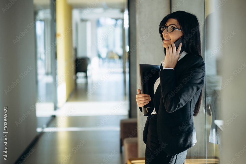 Business woman at the office holding laptop and book
