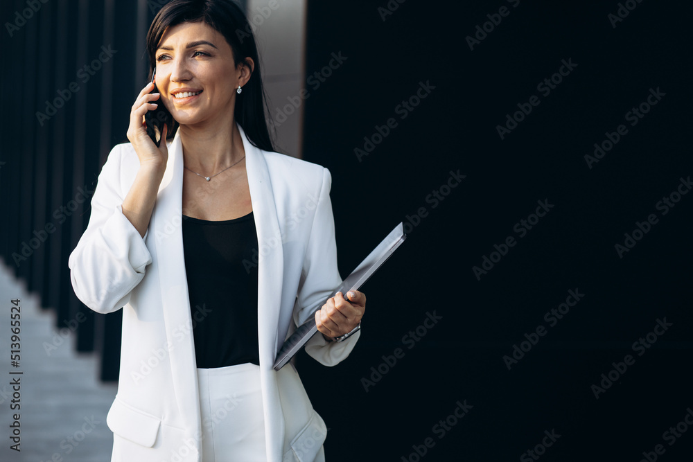 Attractive business woman holding laptop by the office building Attractive business woman holding laptop by the office building