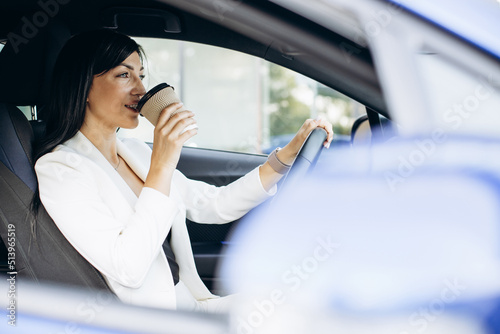 Business woman driving in car and drinking coffee
