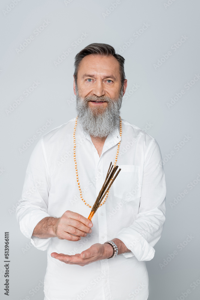 ayurveda master with aroma sticks looking at camera isolated on grey. ayurveda master with aroma sticks looking at camera isolated on grey.